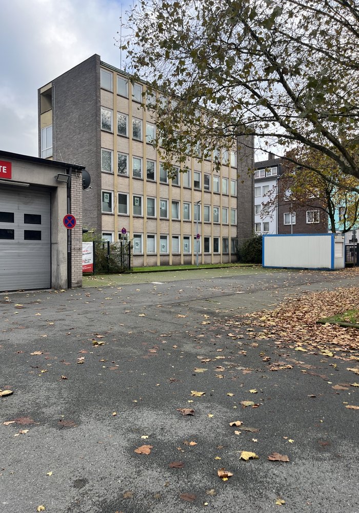 Das alte Verwaltungsgebäude zusammen mit einem Rolltor. Es ist ein etwas heruntergekommener Bau aus den 70ern.