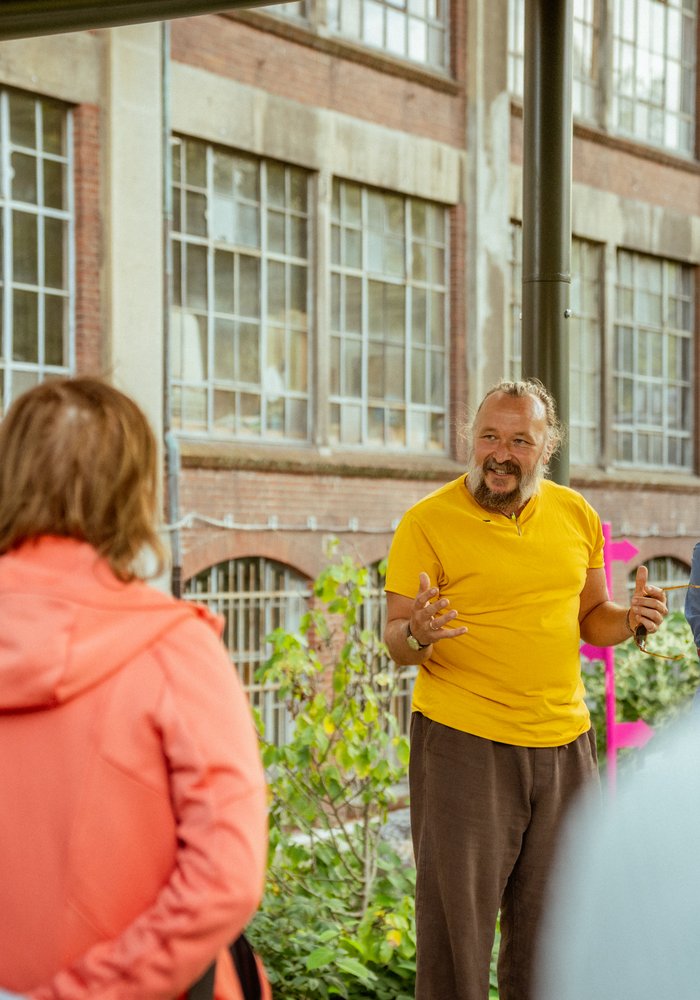 Ein Mann macht eine Führung durch den Garten und erklärt einer Gruppe Menschen etwas