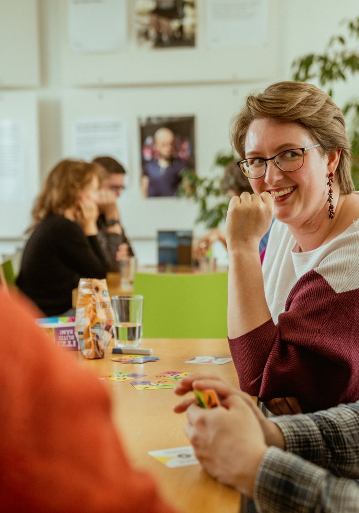Eine Frau unterhält sich mit mehreren Menschen an einem Tisch