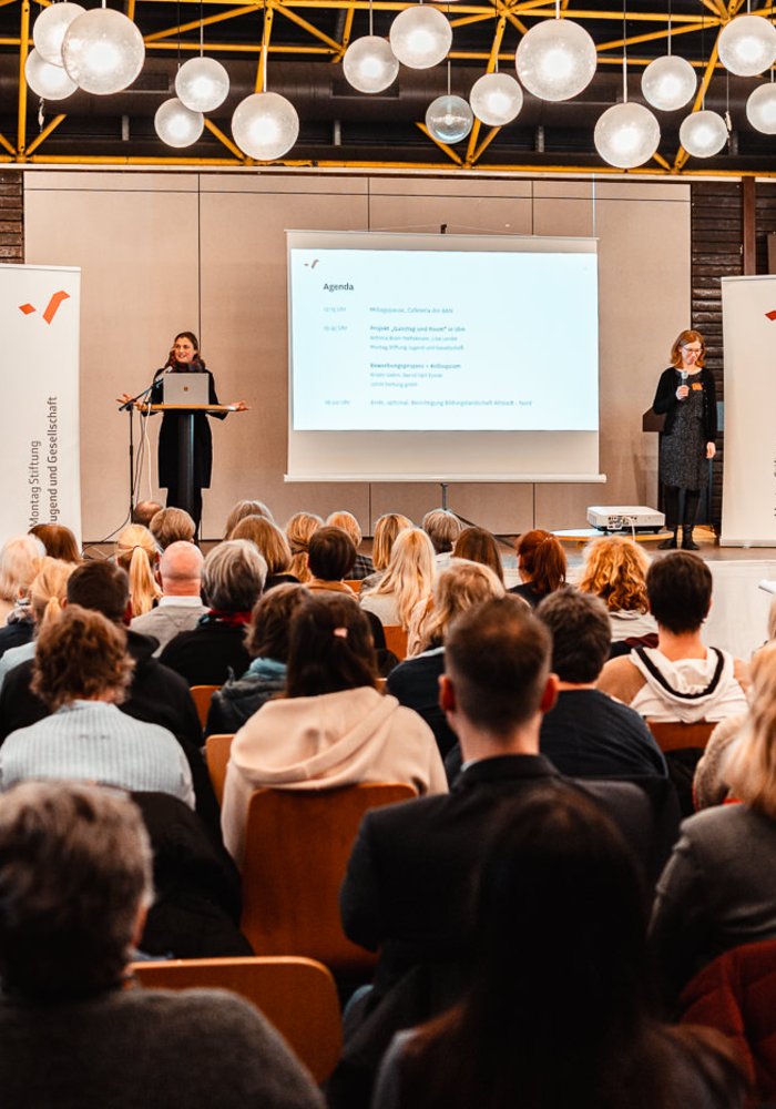 Infoveranstaltung Ganztag und Raum in Köln: Zahlreiche Menschen in Stuhlreihen, auf der Bühne Meike Kricke und Barbara Pampe, Vorständinnen der Montag Stiftung Jugend und Gesellschaft