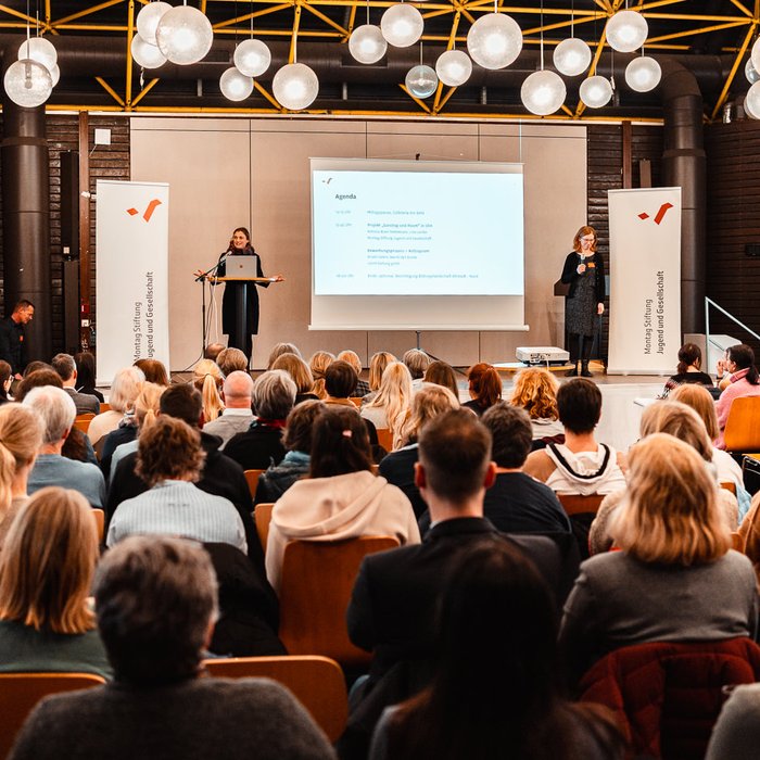 Infoveranstaltung Ganztag und Raum in Köln: Zahlreiche Menschen in Stuhlreihen, auf der Bühne Meike Kricke und Barbara Pampe, Vorständinnen der Montag Stiftung Jugend und Gesellschaft